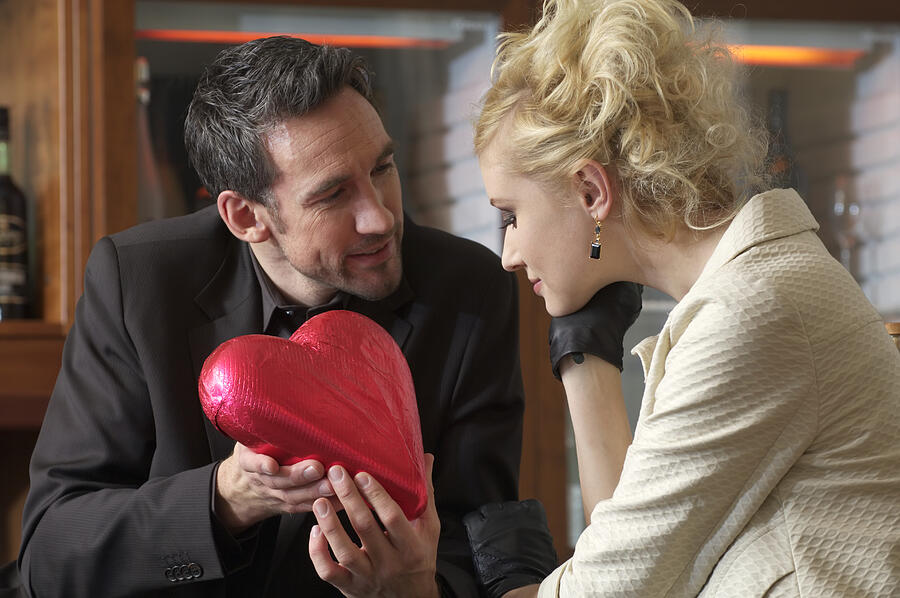 Man giving young woman a chocolate heart Photograph by Stock4b-rf