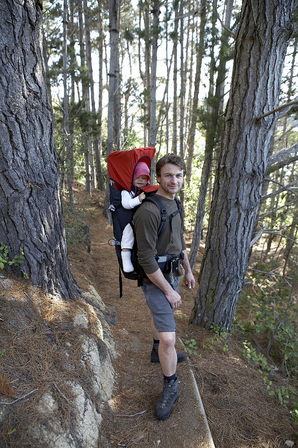 Man hiking with daughter (10-12 months) strapped to back in forest Photograph by Heidi Coppock-Beard