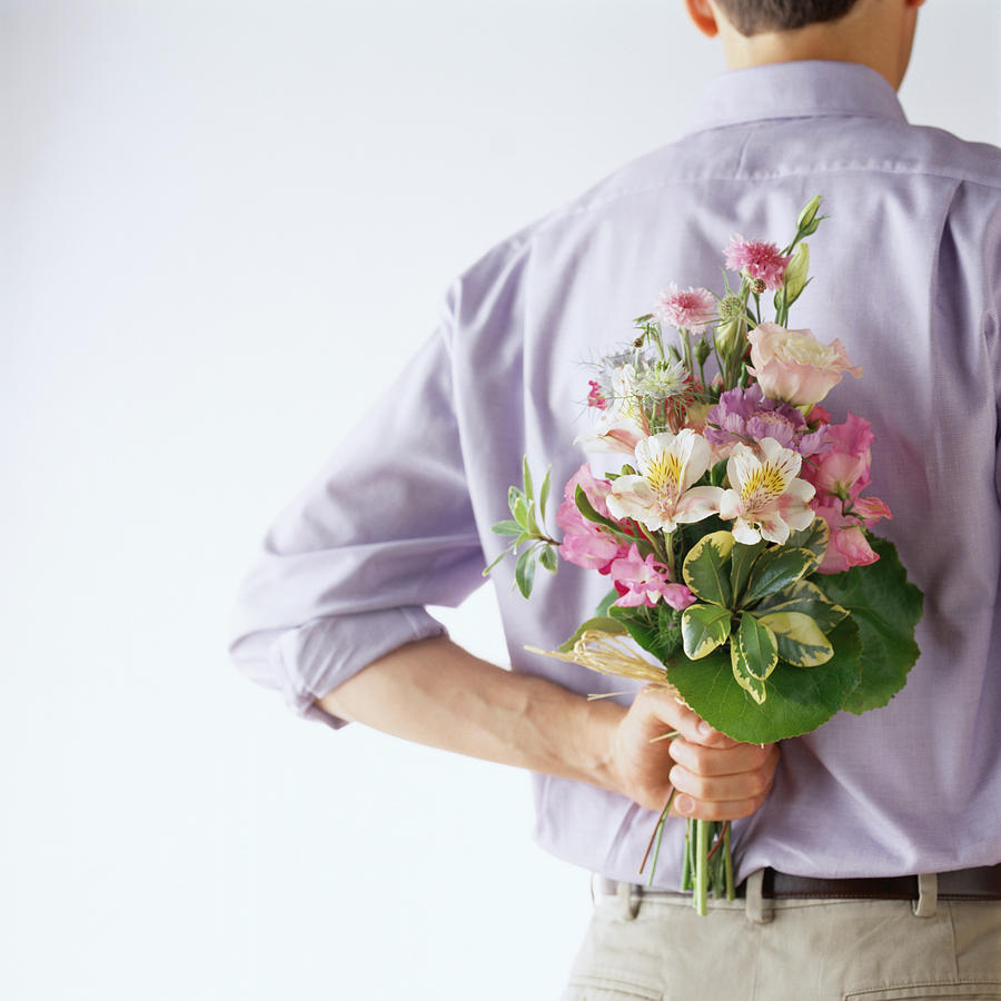 Man Holding a Bouquet of Flowers Behind His Back Photograph by Photodisc