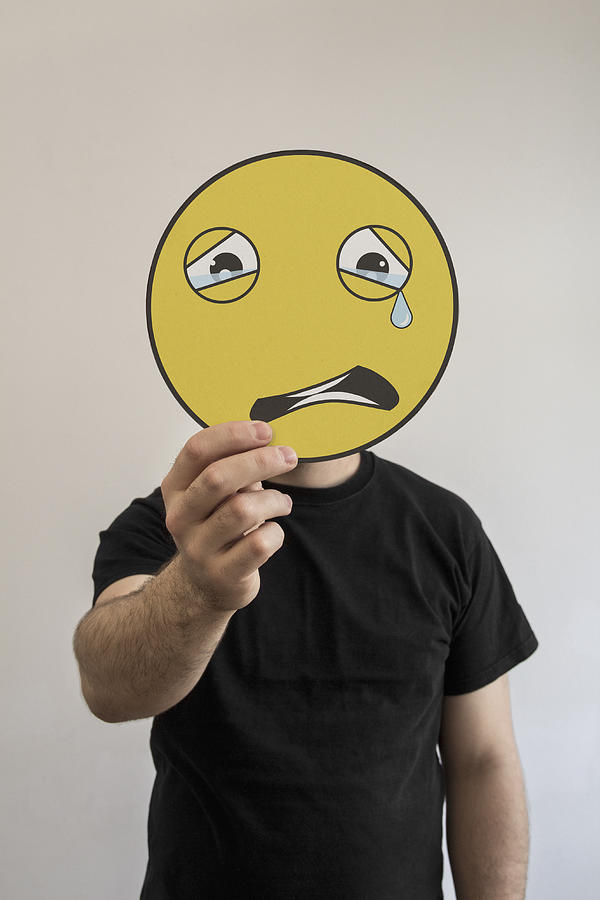 Man holding a crying emoticon face in front of his face Photograph by Malte Mueller