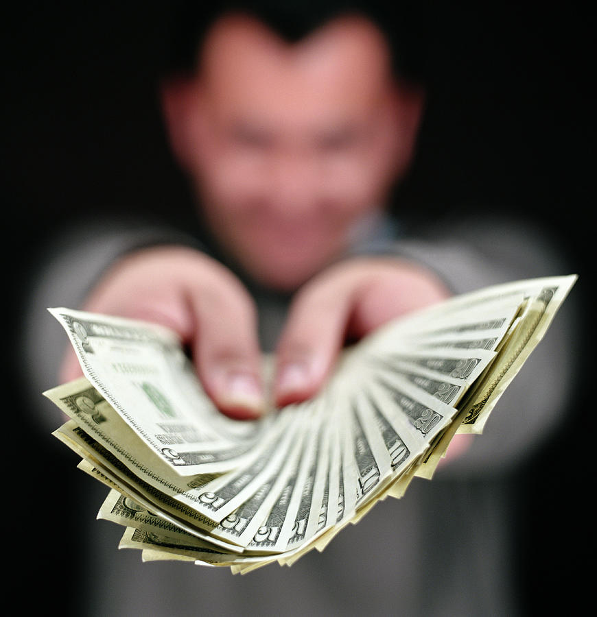 Man holding fan of assorted US dollar bills, focus on money Photograph by Ryan McVay