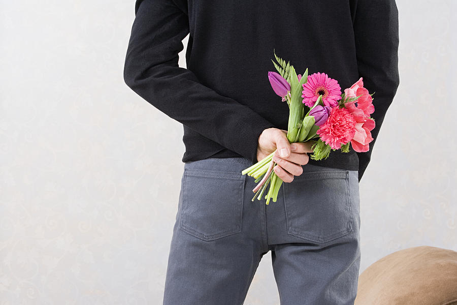 Man holding flowers behind back Photograph by Image Source