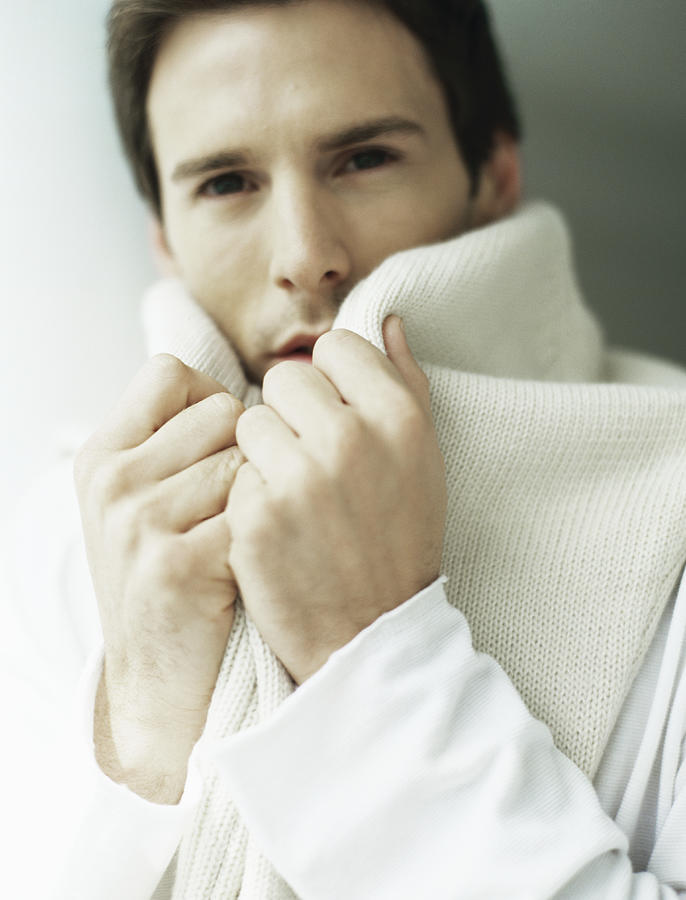 Man holding sweater around neck, covering part of face Photograph by Laurence Mouton