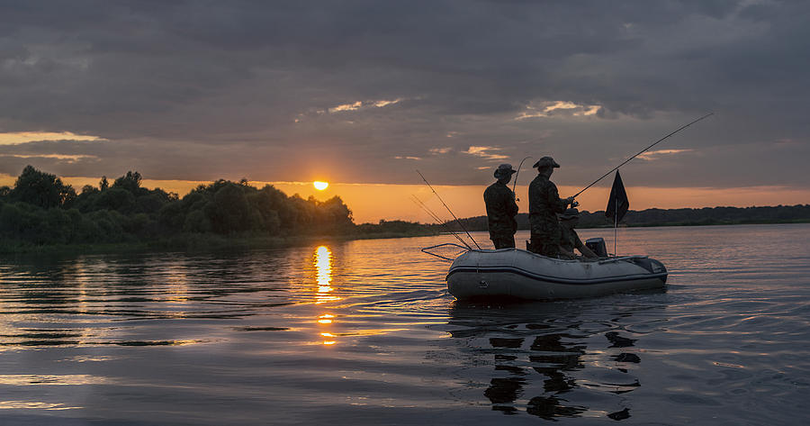 Man in a boat at sunset fish. Photograph by Rogkov