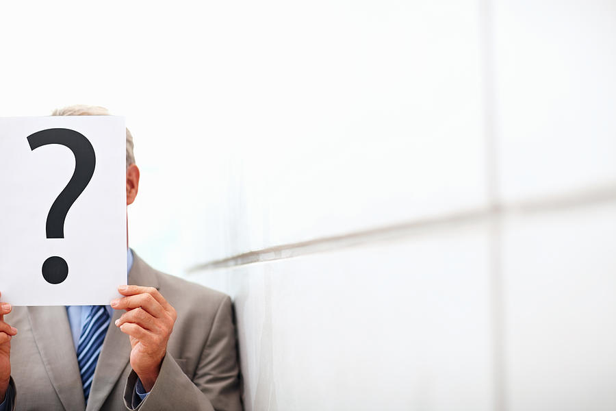 Man in business suit holding question mark sign Photograph by GlobalStock