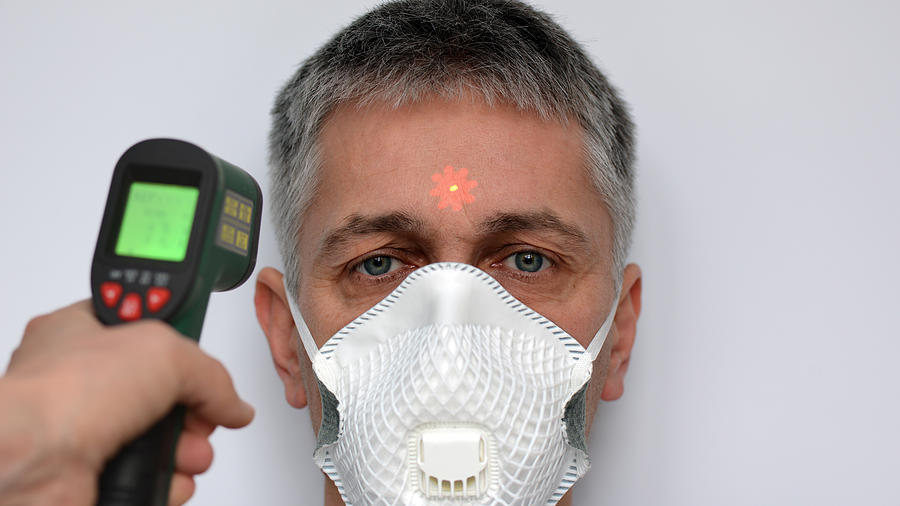 Man in Face Mask Having Temperature Taken With Laser Thermometer Photograph by Jobbys