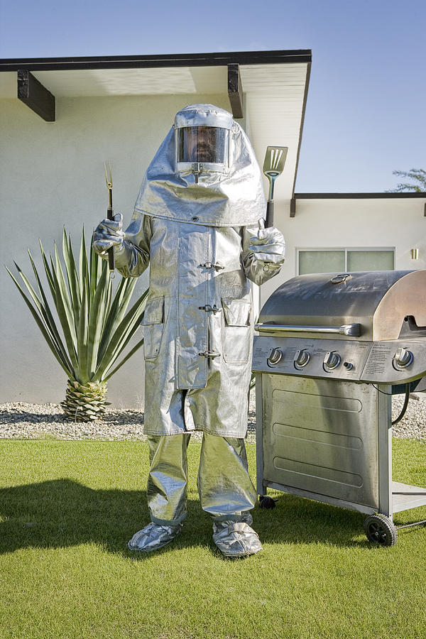 Man in fire-protective suit standing next to grill Photograph by David Zaitz