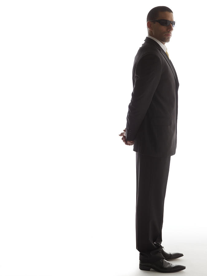 Man in full suit standing with his hands back, side view Photograph by Symphonie