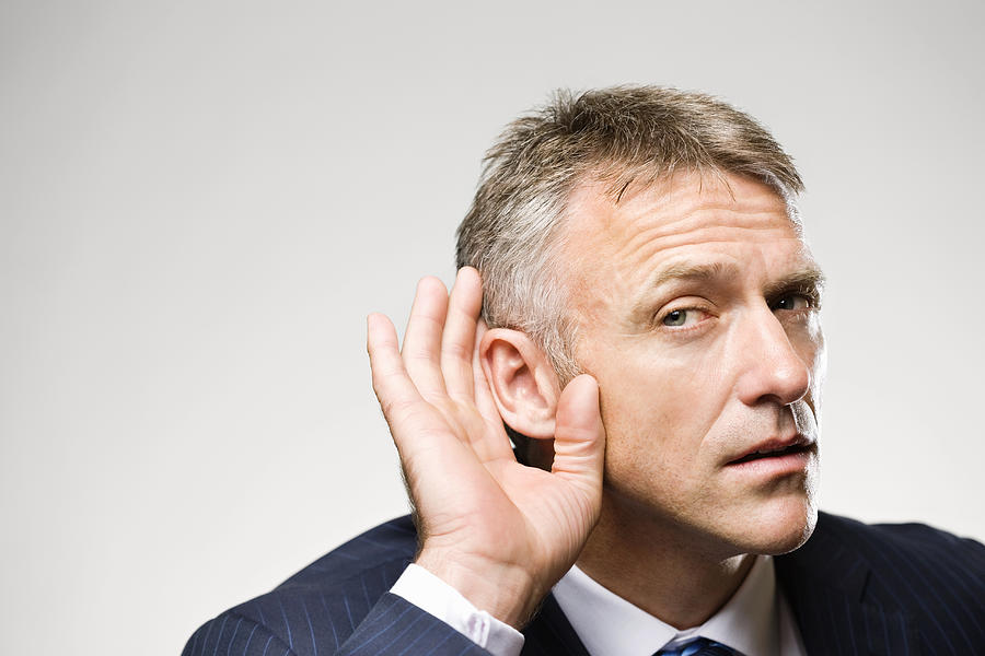 Man in suit cupping his ear with his hand Photograph by Compassionate Eye Foundation/David Oxberry/OJO Images Ltd