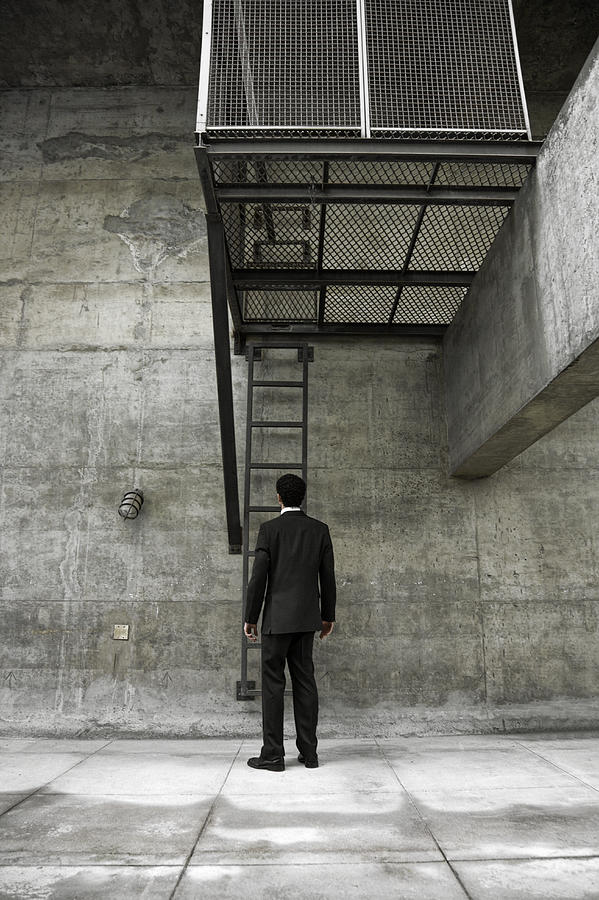 Man in suit standing by ladder in concrete area, rear view Photograph by Emmanuel Faure