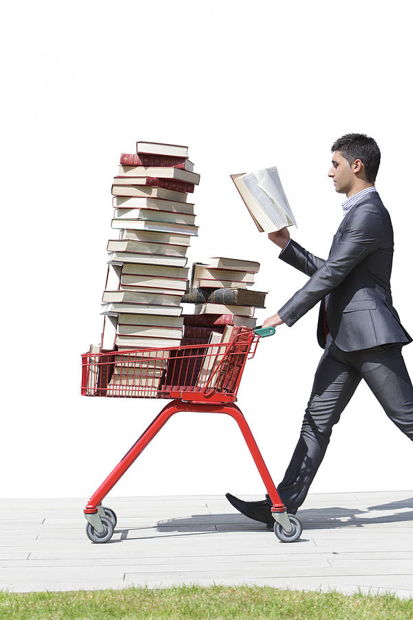 Man In Suit Walking With Books In Trolley Photograph by Peter Cade