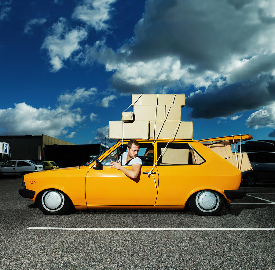 Man in yellow car filled with boxes and tied to roof Photograph by Henrik Weis