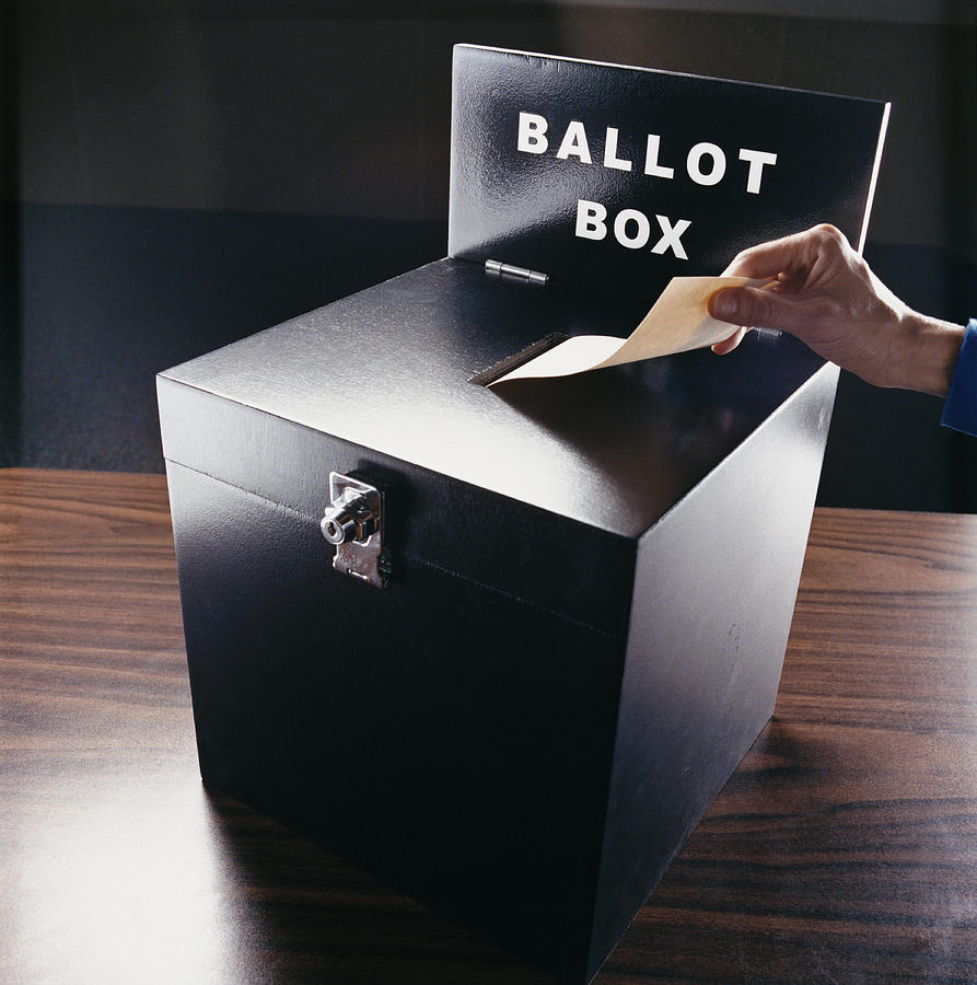 Man Inserting Voting Paper into a Ballot Box Photograph by Digital Vision.