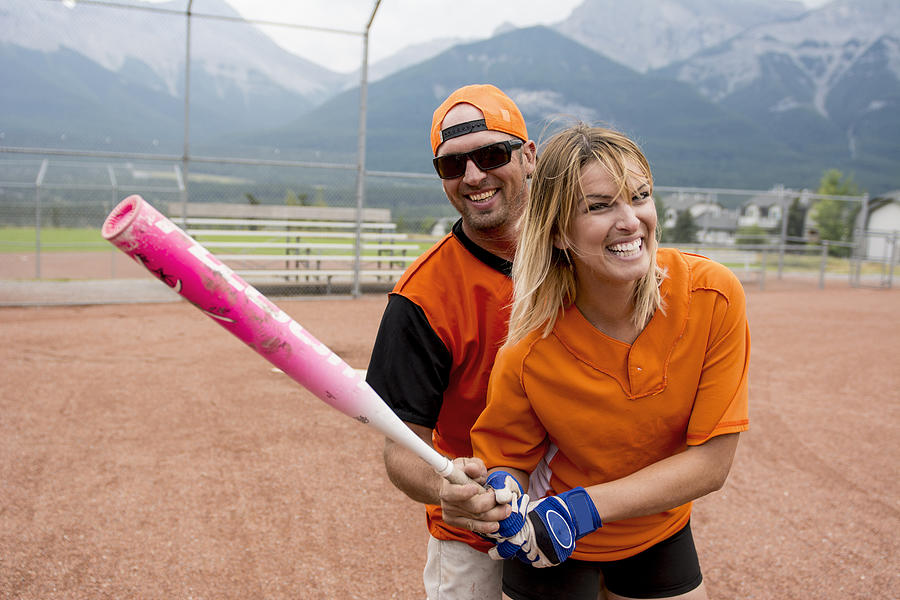 Man instructs woman to improve swing, baseball Photograph by Ascent Xmedia