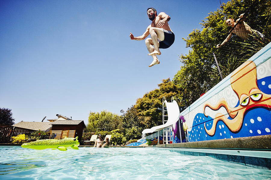 Man jumping from wall into outdoor pool Photograph by Thomas Barwick