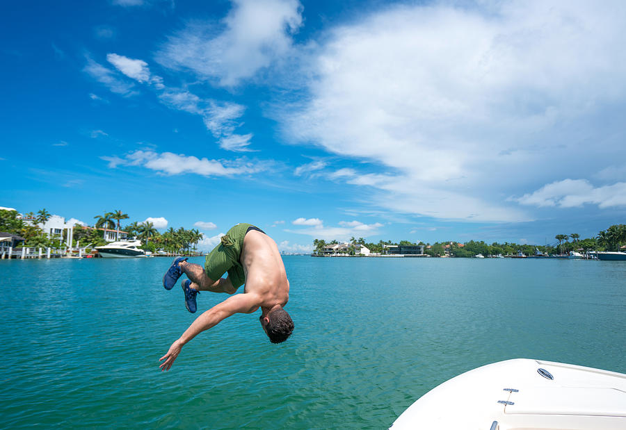 Man jumping off boat Photograph by Thepalmer