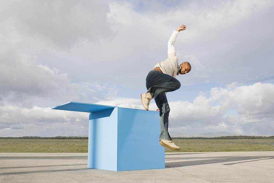 Man jumping out of large blue box Photograph by Martin Barraud