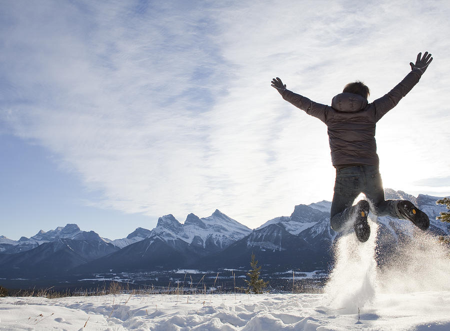 Man jumps for joy in snowy mountain meadow Photograph by Ascent/PKS Media Inc.