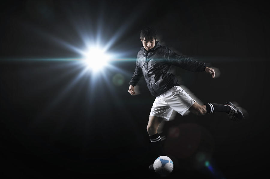 Man kicking a soccer ball Photograph by Yagi Studio