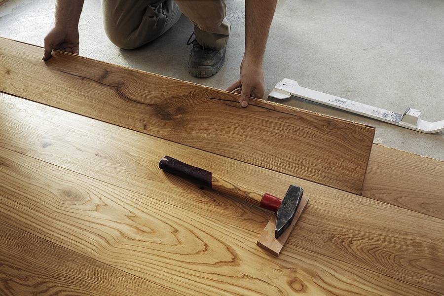 Man laying finished parquet flooring, close-up Photograph by Westend61