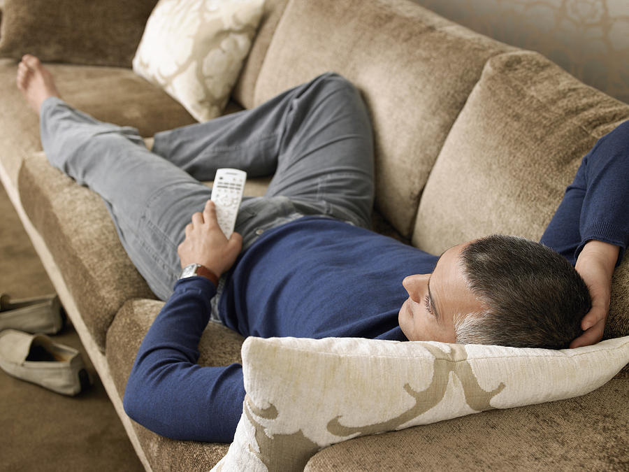 Man Laying on Sofa Watching TV Photograph by Moodboard
