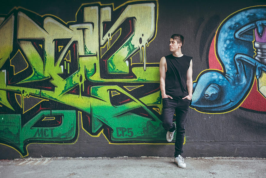 Man leaning on graffiti wall Photograph by Urbazon
