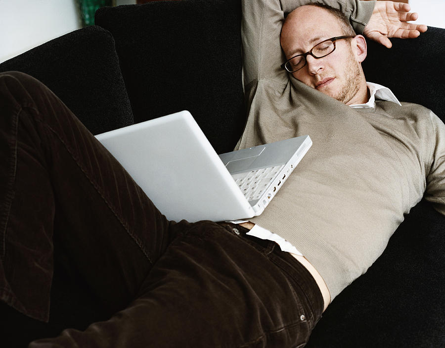 Man Lies on a Sofa, Sleeping, a Laptop on His Lap Photograph by Dylan Ellis