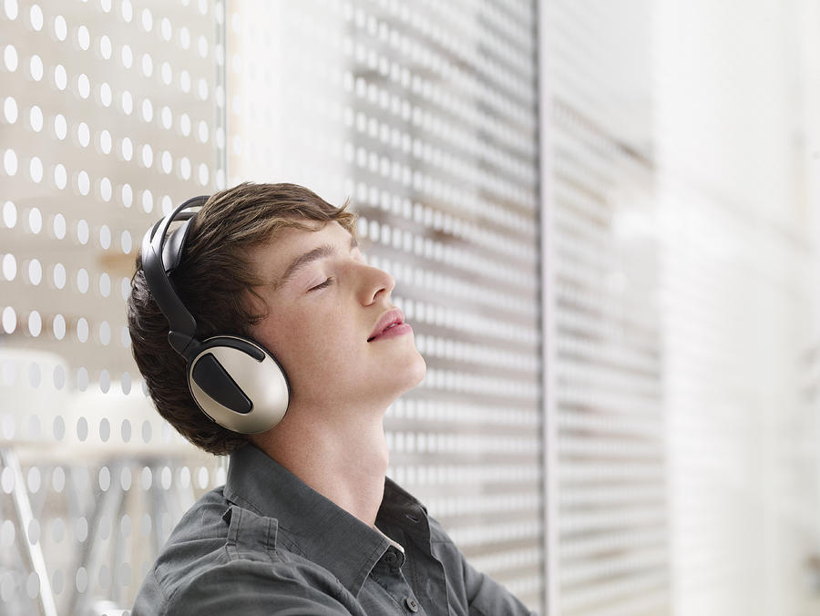 Man listening to headphones with eyes closed Photograph by Martin Barraud