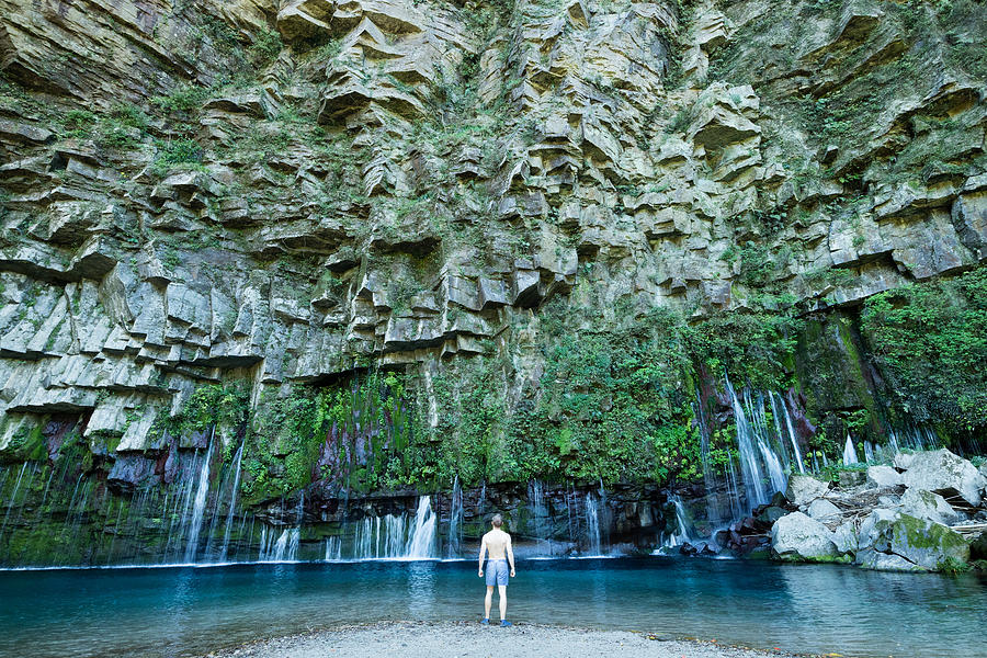Man looking at beautiful waterfall lagoon Photograph by Sam Spicer