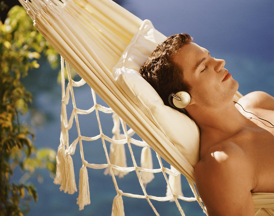Man Lying in Hammock Listening to Headphones Photograph by Flying Colours Ltd