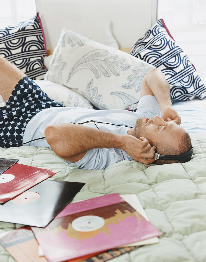 Man Lying on a Bed Wearing Headphones Surrounded by Records Photograph by A J James