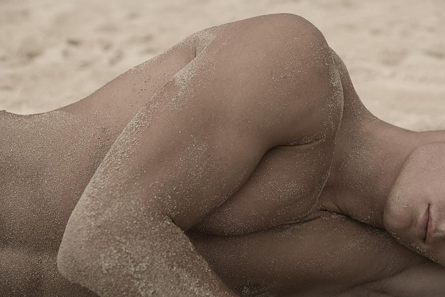 Man lying on a sandy beach Photograph by Image Source