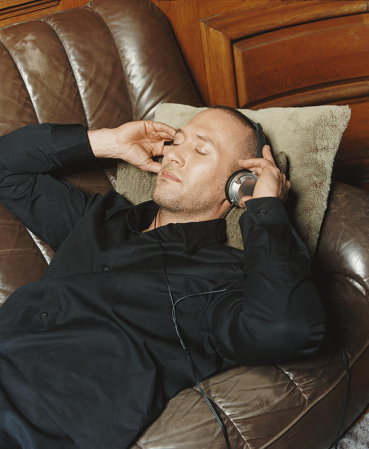 Man Lying on a Sofa Listening to Music on Headphones Photograph by A J James