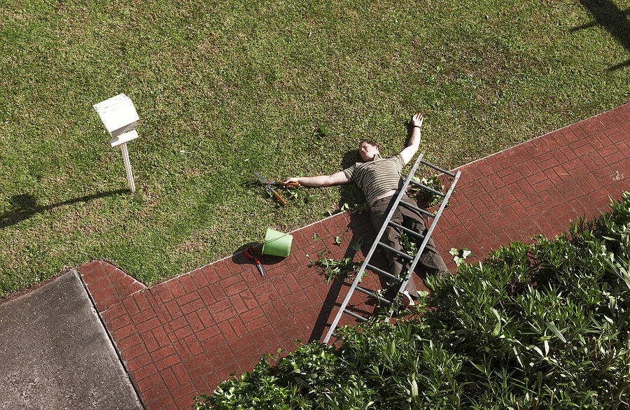 Man lying on ground with ladder on top of him Photograph by Nick Bowers