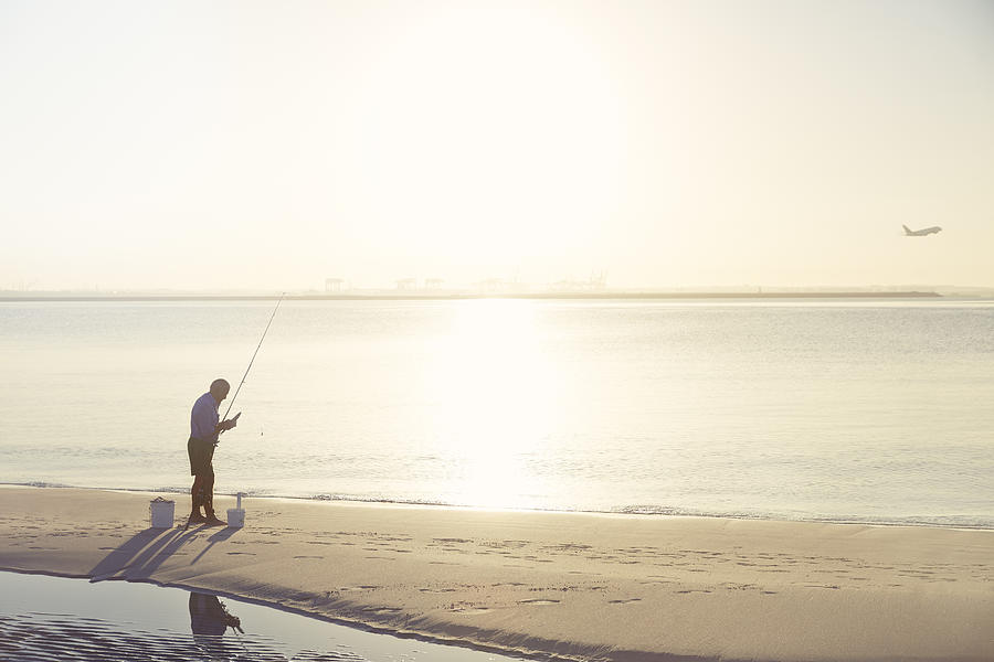 Man On Beach Fishing On Golden Morning. Photograph by Stuart Ashley