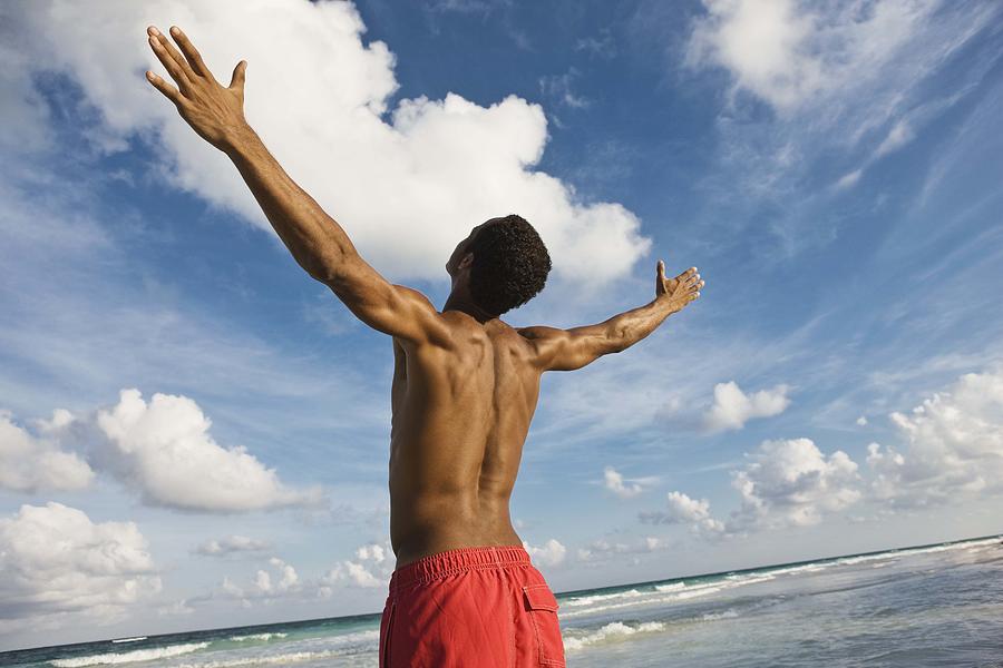 Man on beach with arms outstretched Photograph by Jupiterimages
