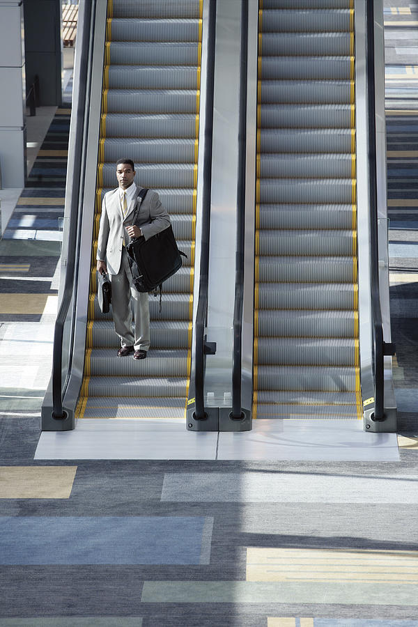 Man on escalator Photograph by Comstock Images