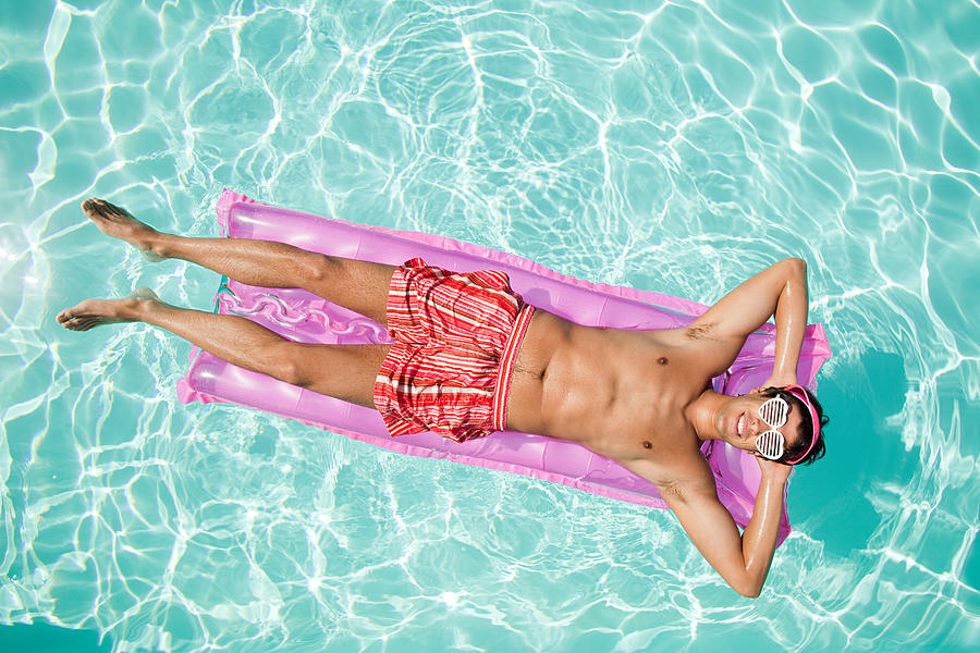 Man on inflatable mattress in pool Photograph by Image Source