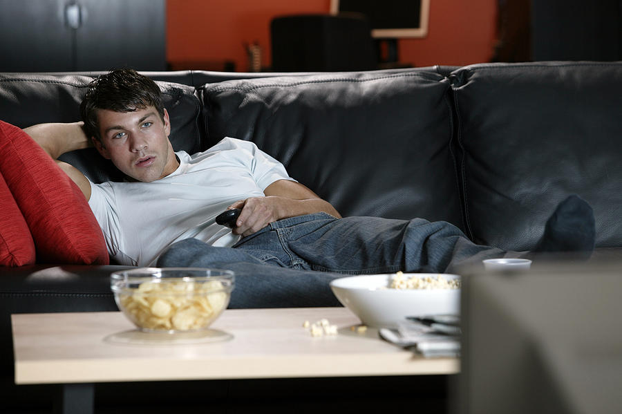 Man on sofa watching television Photograph by Comstock Images
