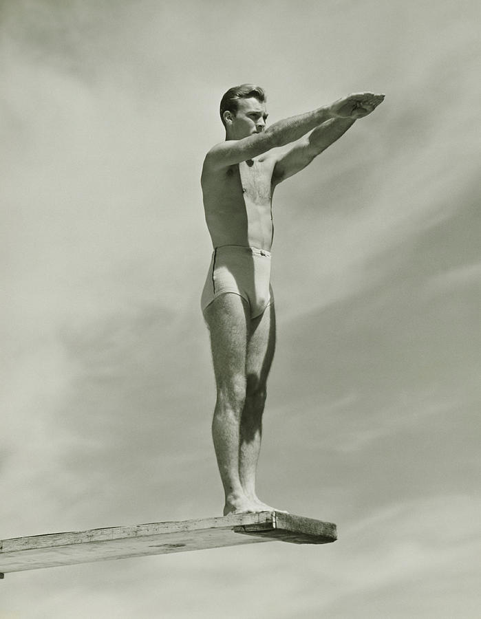 Man on springboard ready to jump, (B&W), low angle view Photograph by George Marks