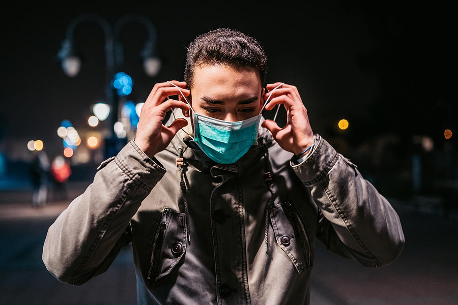 Man on street protecting himself from viruses with mask Photograph by Urbazon