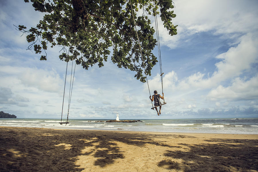 Man on swing by the sea Photograph by David Trood