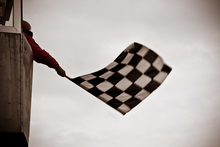 Man on tower waving checkered flag Photograph by Stevedangers