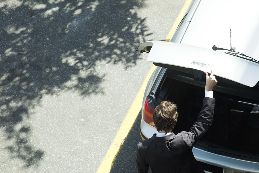 Man opening car hatchback Photograph by PhotoAlto/Ale Ventura