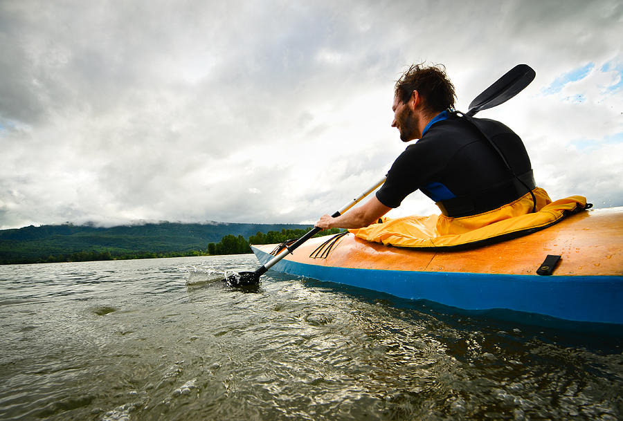 Man paddling in wooden kayak Photograph by Thinair28