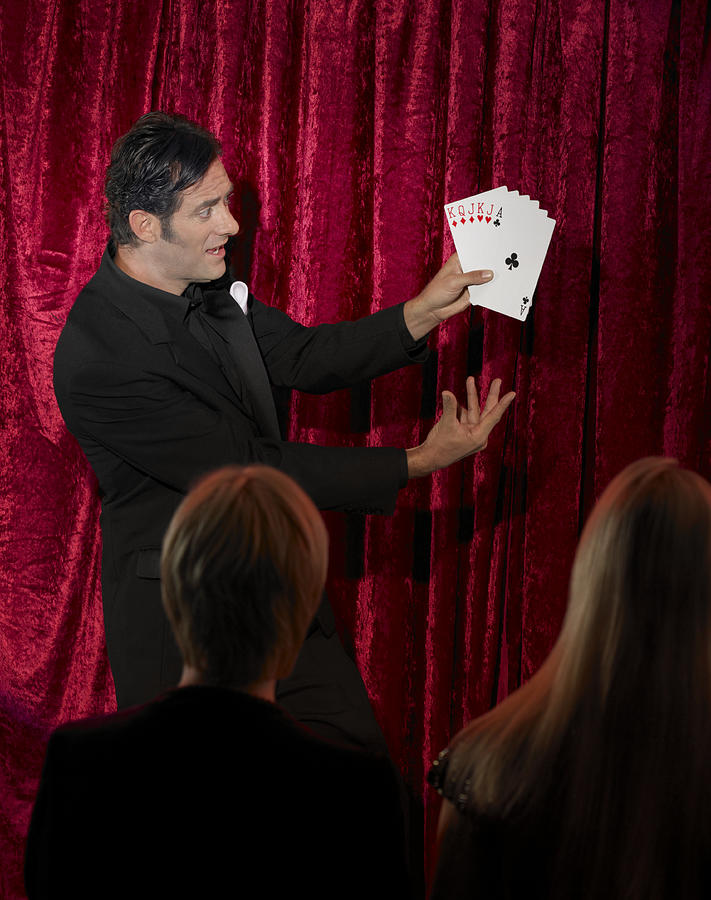 Man performing card trick on stage Photograph by John Rowley