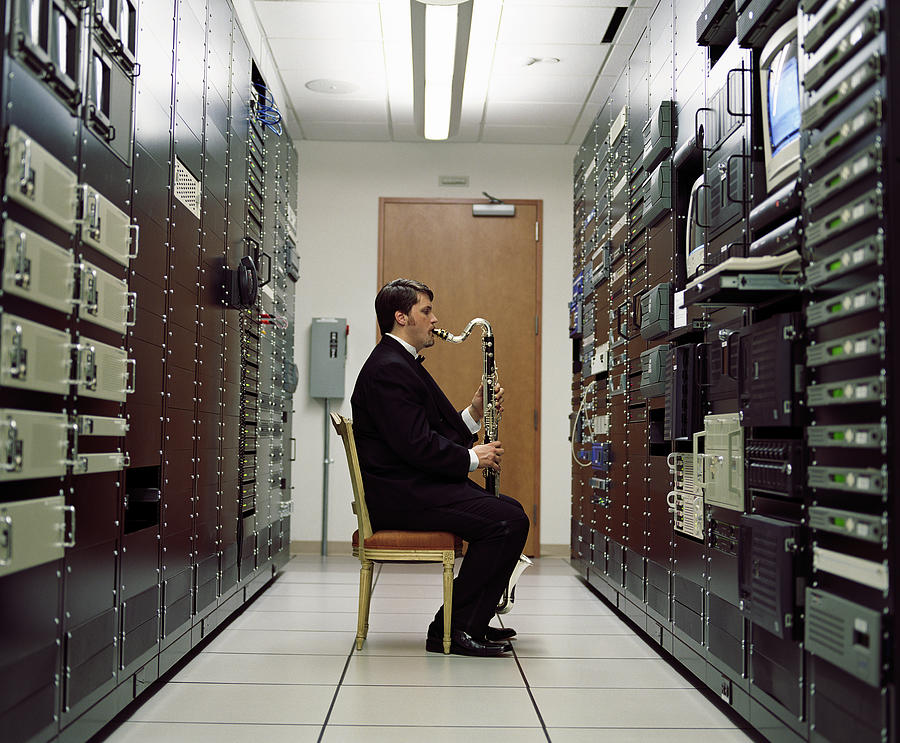 Man playing bass clarinet in server room, side view Photograph by Ryan McVay