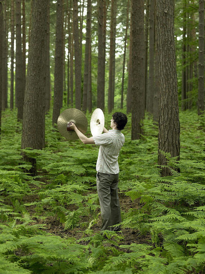 Man playing cymbals in forest, rear view Photograph by Michael Blann