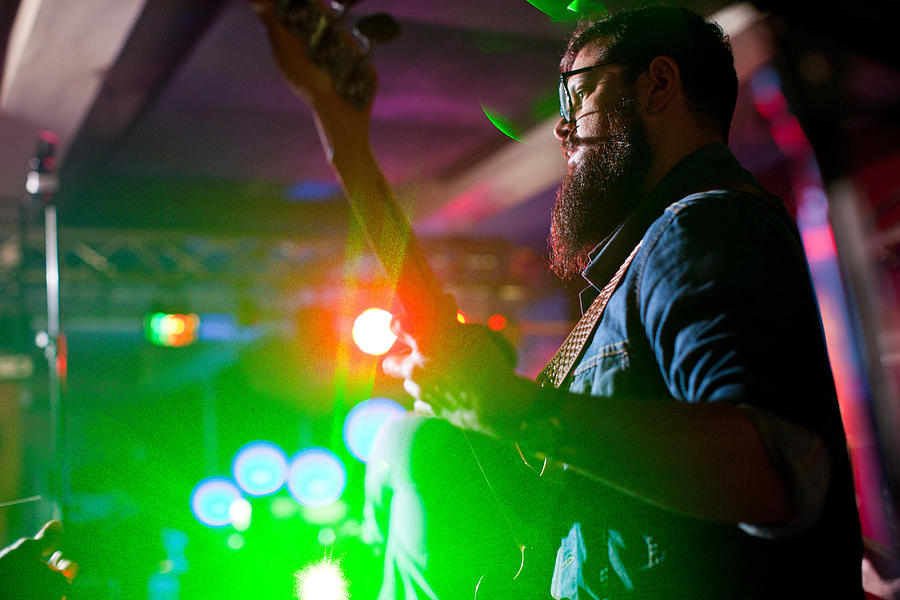 Man playing guitar in nightclub Photograph by Zero Creatives