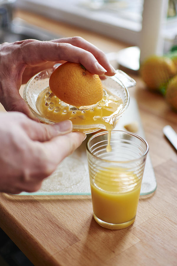 Man pouring freshly squeezed orange juice into a jar Photograph by Westend61